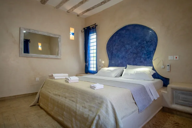 A double bed under a deep-blue arched headboard in a one-bedroom apartment
