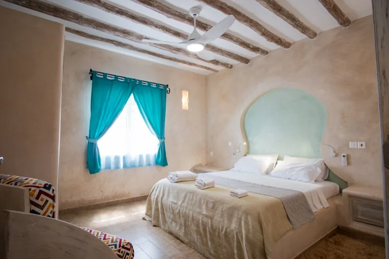 A bright double bedroom with turquoise curtains in a two-bedroom apartment