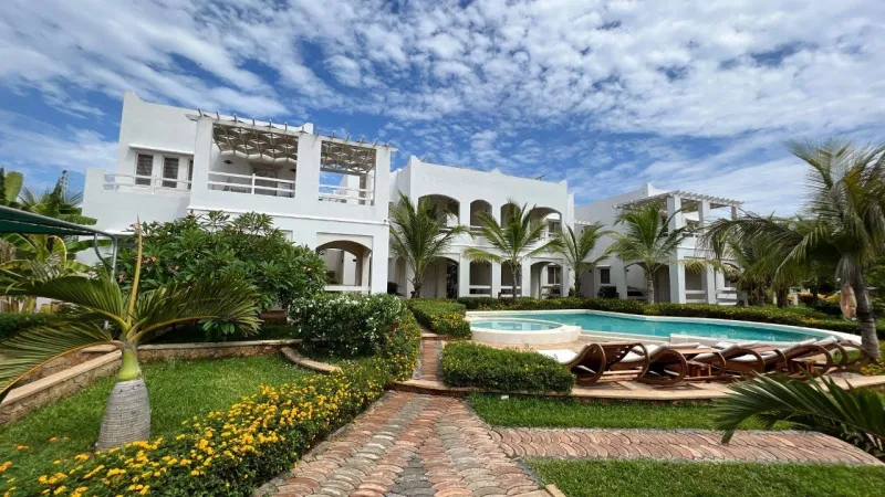 The white apartment blocks behind the garden and pool