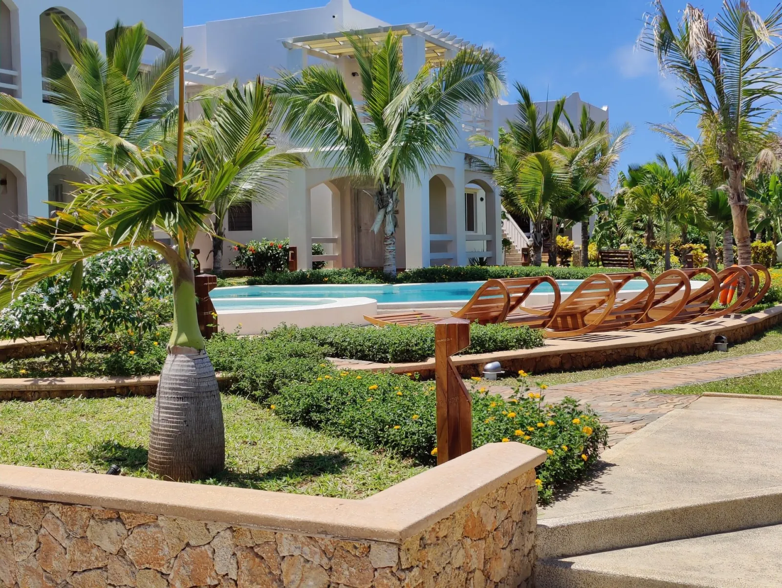 Palms and sun loungers around the pool at Agama Apartments, Watamu