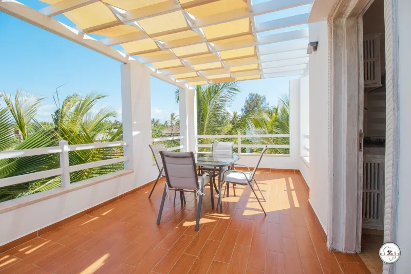 The terrace under a pergola with palms beyond