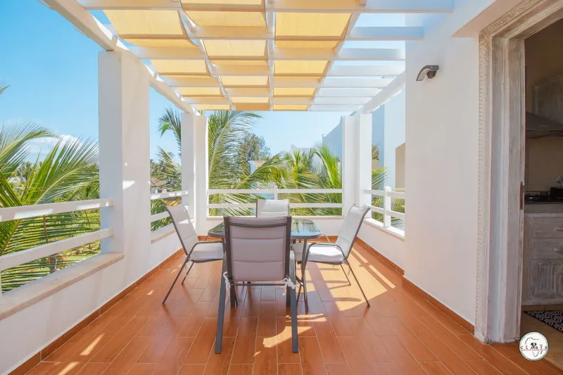 A shaded terrace with a table and chairs